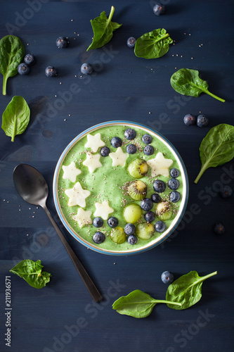 healthy green spinach smoothie bowl with blueberry, apple stars, kiwi, chia seed