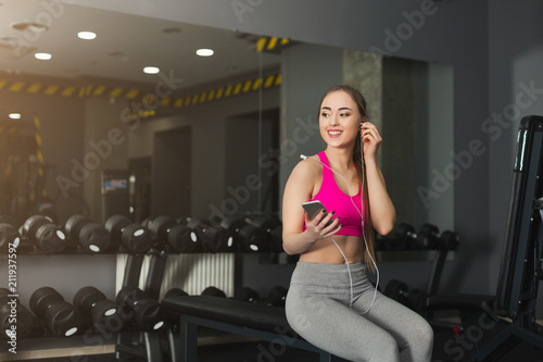 Fitness girl in headphones choose music on phone