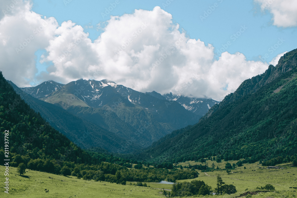 green mountain valley landscape with river and cloudy sky
