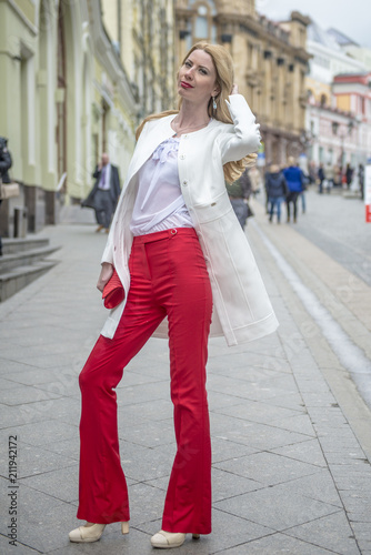 Fashionable young blonde in a spring fashionable suit and with a shopping bag in the center of Moscow
