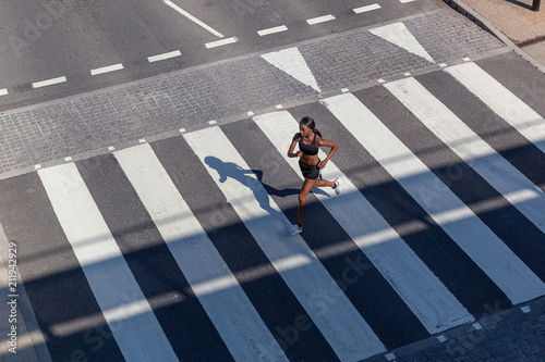 Young woman running on zebra crossing photo