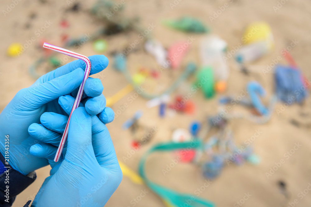 Man holding drinking straw from plastic pollution collected on beach