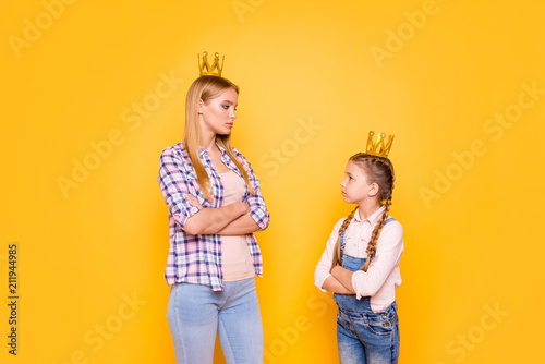 Stepsister adopted mom mum mommy concept. Portrait of upset sad beautiful angry girls standing with crossed folded hands looking into eyes wearing overalls checkered shirt isolated bright background