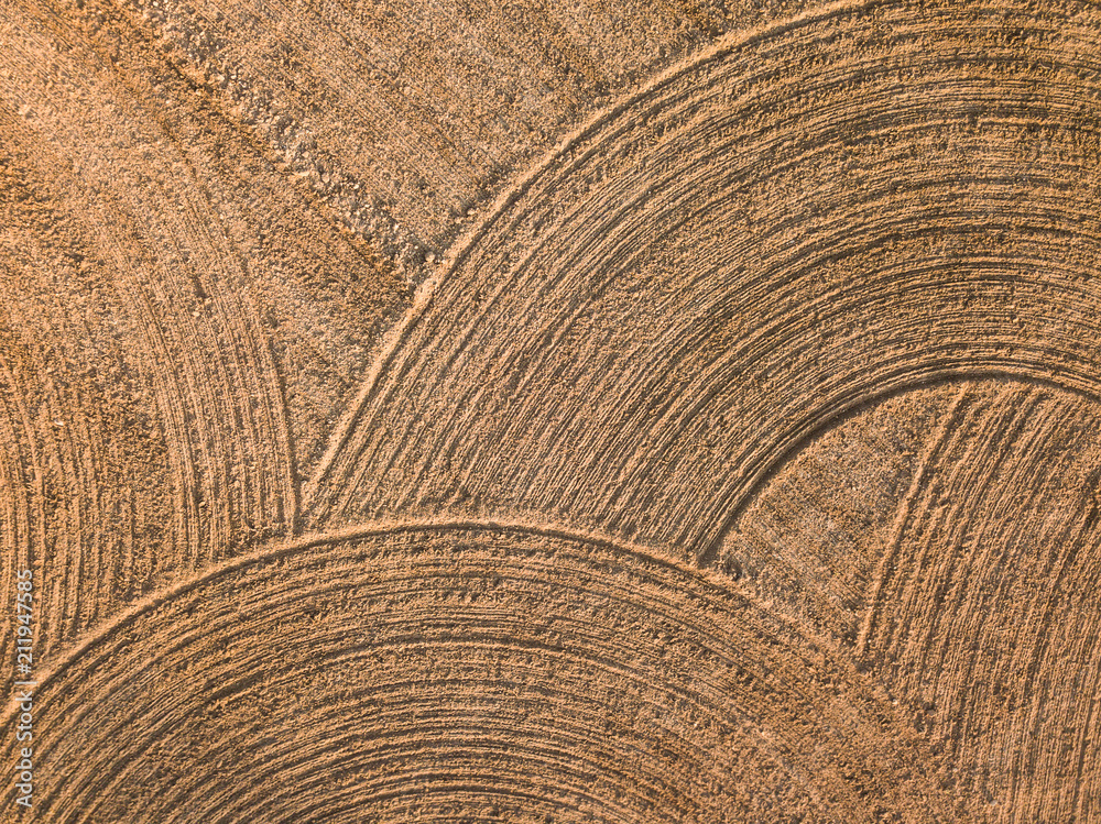 Fototapeta premium Spring arable land. Field and beautiful patterns from the tractor. View from above. 