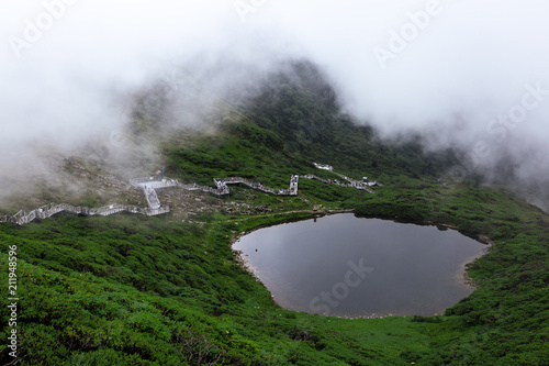 Xima Pond on the top of Mount Cangshan, with people walking along the path in the background. Legend has it that Kublai Khan led his army passing the mountain and washed his horse here. photo