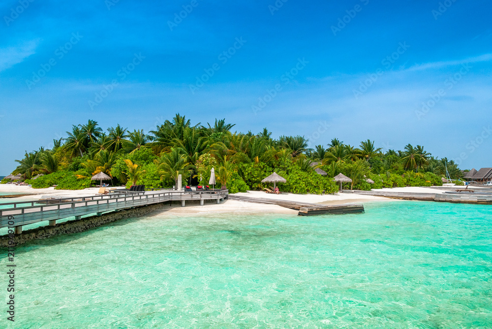 A peer to the paradise island with green palms and snow-white sand beach 