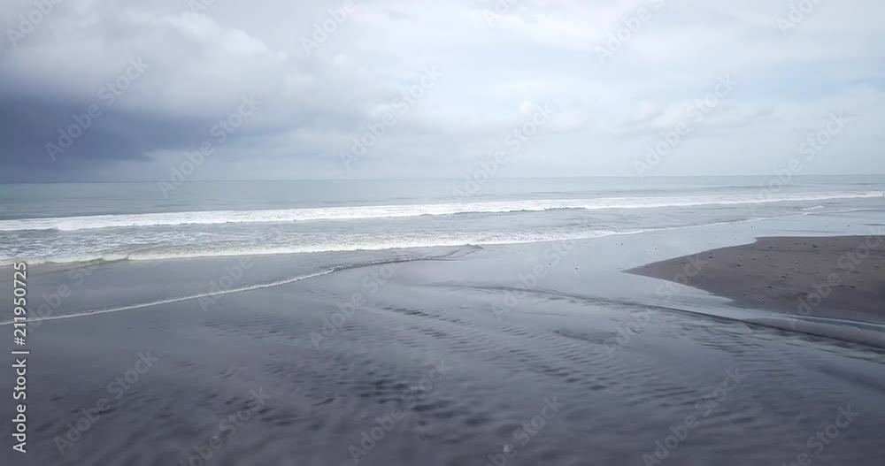 Young handsome hipster man riding modern custom motorcycle cafe racer on the black sand beach near the water. Adventure and travel concept. Surfing spot with ocean waves. Aerial drone footage. Young handsome hipster man riding modern custom motorcycle cafe racer on the black sand beach near the water. Adventure and travel concept. Surfing spot with ocean waves. Aerial drone footage.