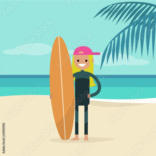Young happy surfer wearing a wetsuit and holding a surfboard