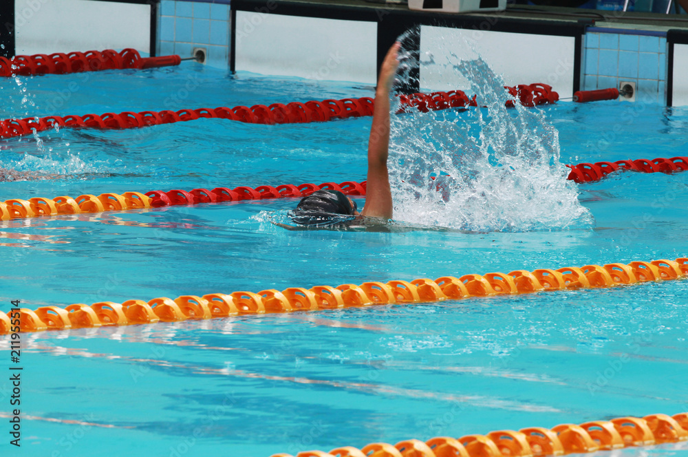 Young swimmer practice backstroke or back crawl in swimming pool for competition or race