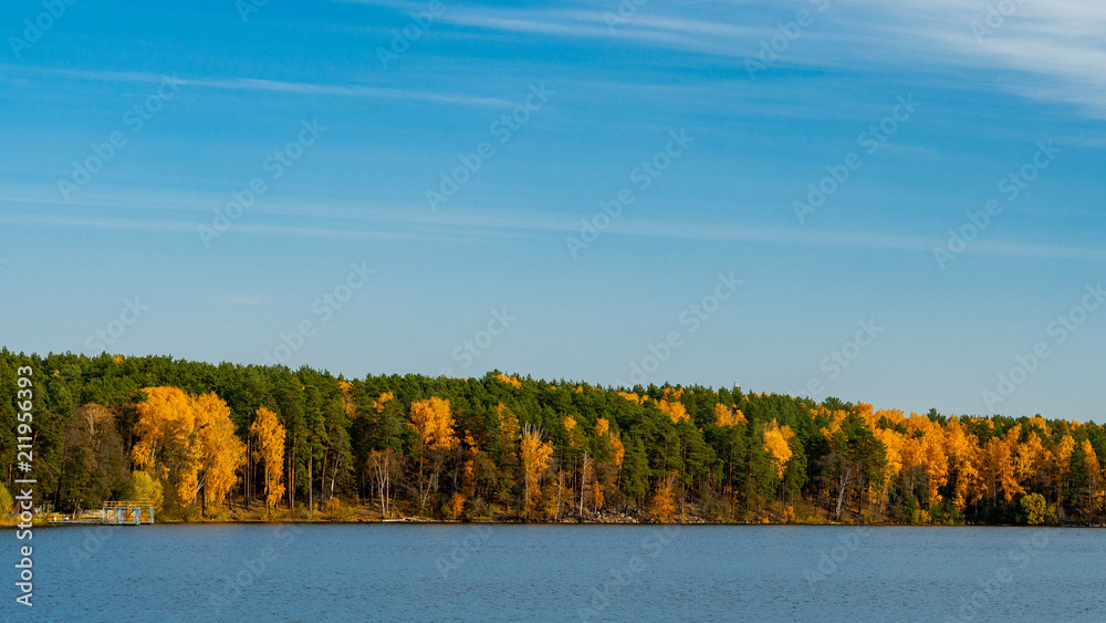 Panorama of the lake with autumn mixed forest on the sides