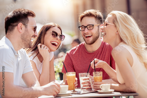 Four laughing friends enjoying coffee in a cafe