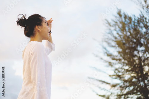 Young woman looking far away in a park during sunset.