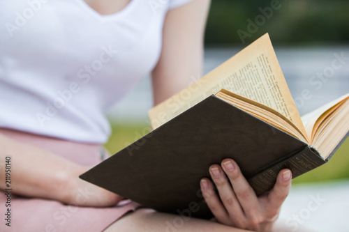Young woman holding an old book in her hands outdoors