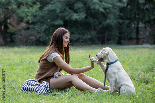 Dog taking five to girl while sitting on the green grass in park © pucko_ns