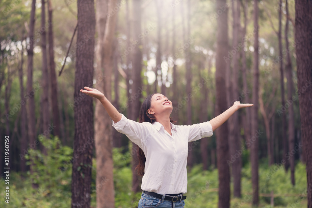 Christian worship with raised hand in pine forest,Happy woman deep breath fresh air in nature breathing clean air. Female enjoying nature and praying to god.