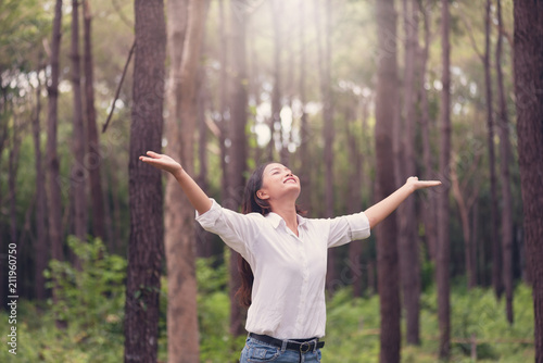 Christian worship with raised hand in pine forest Happy woman deep breath fresh air in nature breathing clean air. Female enjoying nature and praying to god.