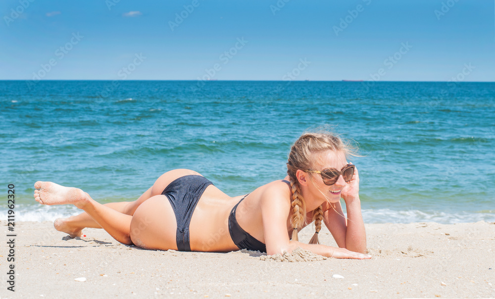 Beautiful slim woman in bikini lying on sand on the beach Beautiful slim woman in bikini lying on sand on the beach