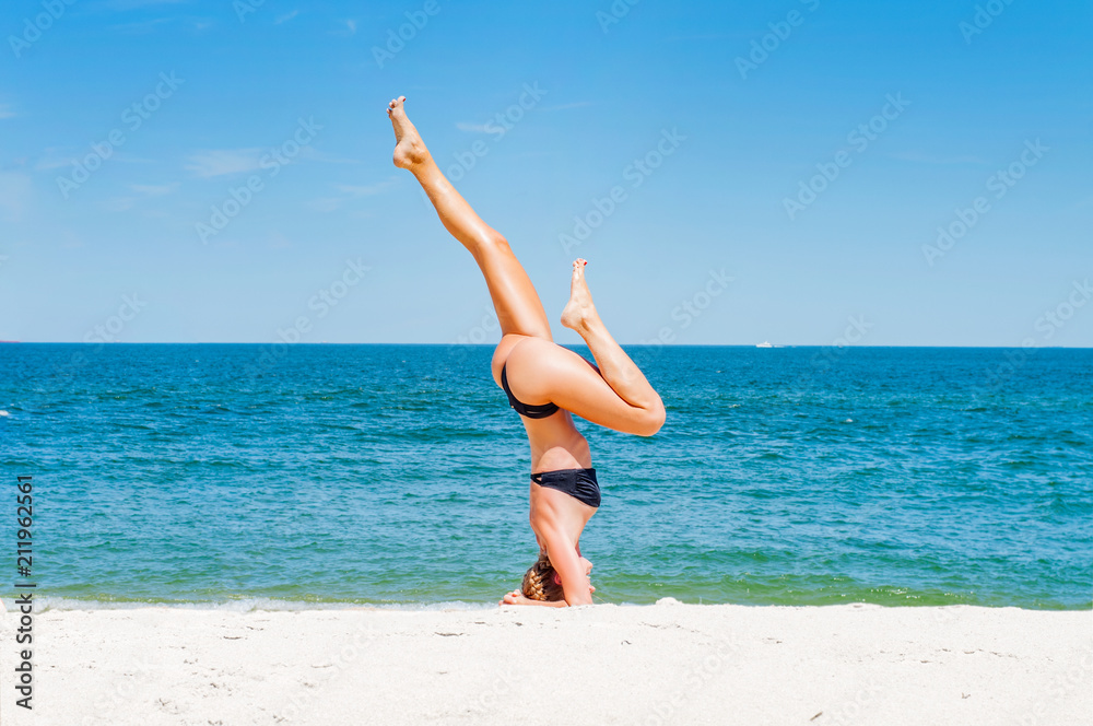 Beautiful young woman doing yoga on beach