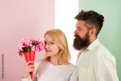 Woman enjoy fragrance bouquet flowers. Couple in love happy celebrate anniversary. Man with beard takes care about girlfriend happiness. Lady likes flower husband gifted her. Flowers delivery concept