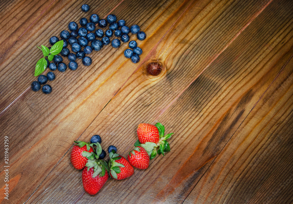 Frame with blueberries, blueberries, strawberries on a wooden table. Place for phrase
