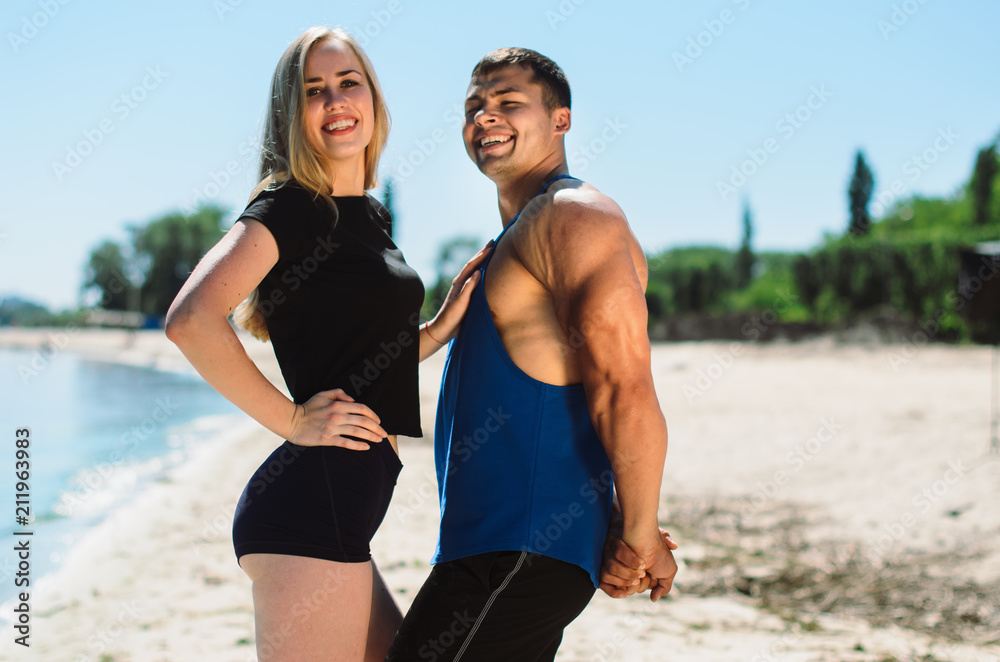 the athlete on the beach posing. the guy with the girl in sportswear together the athlete on the beach posing. the guy with the girl in sportswear together