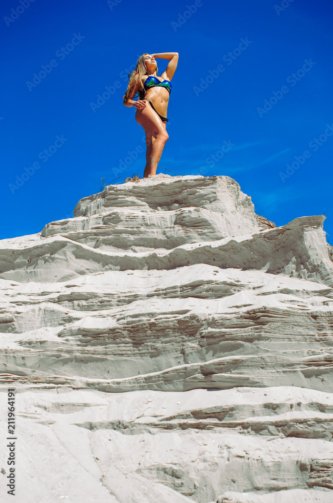 A man stands on a mountain of rage . The athlete reaches the top. Posing on a pedestal. athletes on the beach, a fitness model posing in bikini.