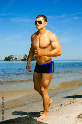 athletes on the beach  a fitness model posing . the guy runs along