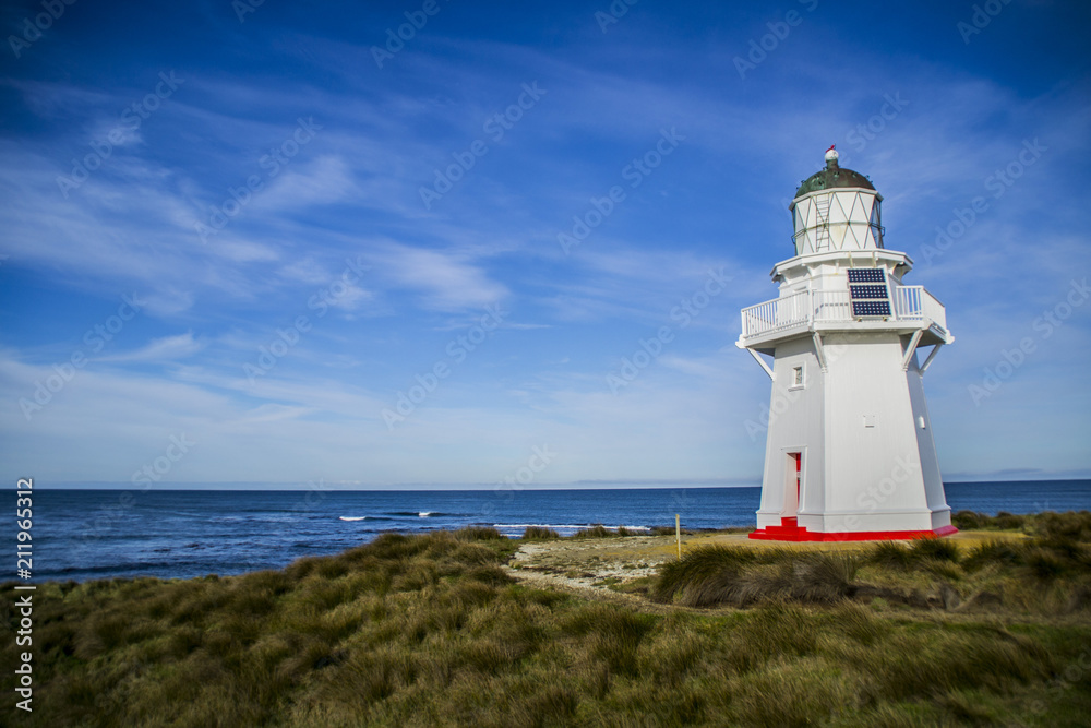 Travel New Zealand. Scenic view of white lighthouse on coast, ocean, outdoor background. Popular tourist attraction, Waipapa Point Lighthouse located at Southland, South Island. Travel concept.