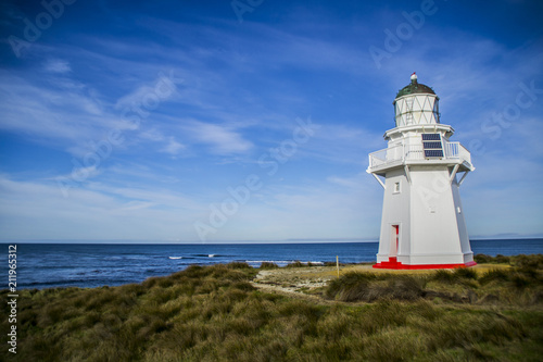 Travel New Zealand. Scenic view of white lighthouse on coast, ocean, outdoor background. Popular tourist attraction, Waipapa Point Lighthouse located at Southland, South Island. Travel concept.