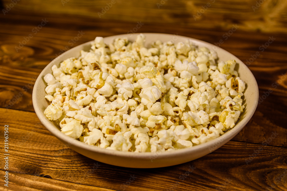 Ceramic plate with popcorn on wooden table Ceramic plate with popcorn on wooden table