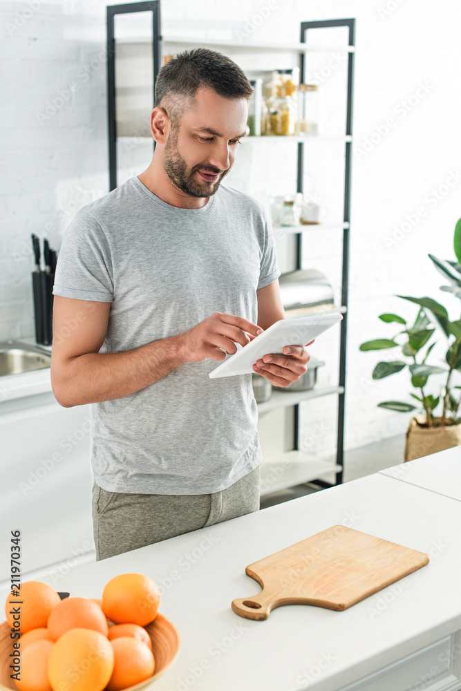 happy man using digital tablet near table on kitchen happy man using digital tablet near table on kitchen