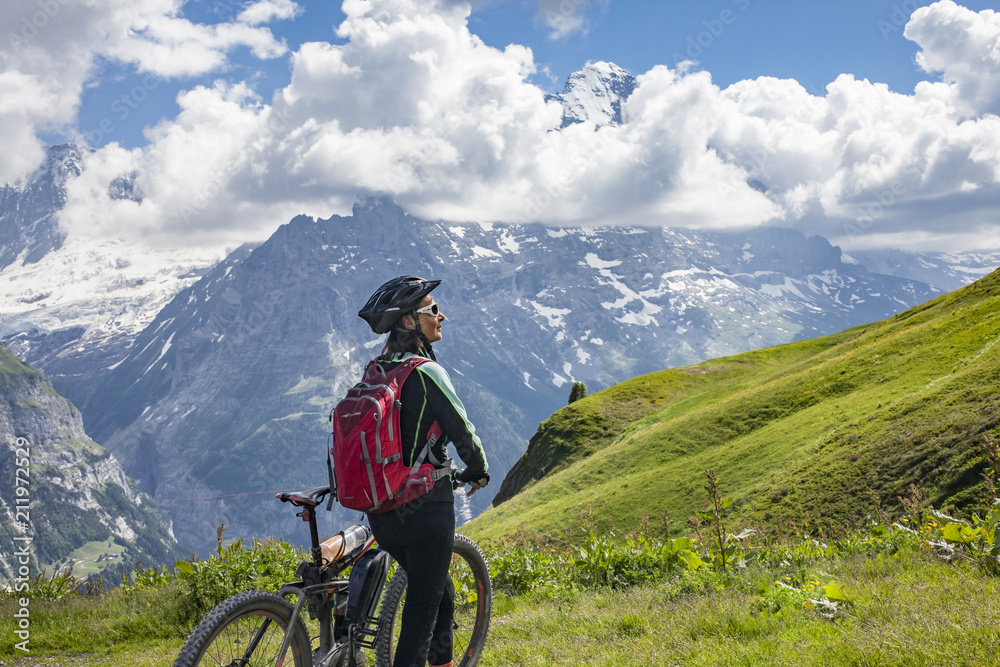 nice and ever young senior woman riding her e-mountainbike below the Eiger Northface near Grindelwald and Wengen, Jungfrauregion, Switzerland nice and ever young senior woman riding her e-mountainbike below the Eiger Northface near Grindelwald and Wengen, Jungfrauregion, Switzerland