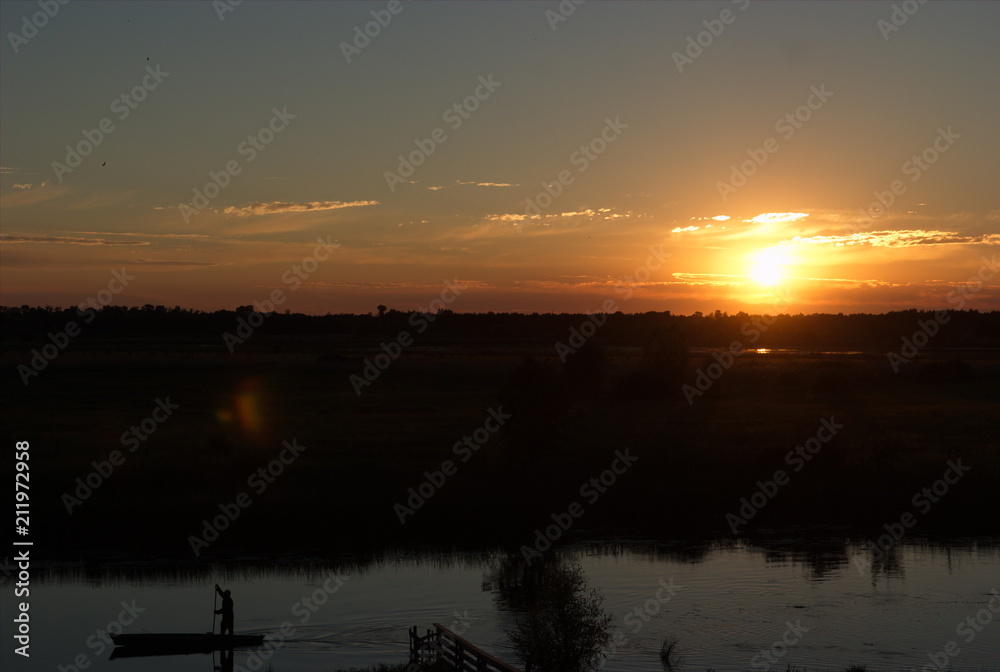 Fototapeta premium Astonishing sunset on the river with the man on his boat