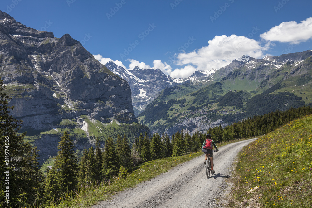 nice senior woman, riding her e-mountainbike on the Lauberhorn downhill from Kleine Scheidegg to Wengen and Lauterbrunnen,Jungfrauregion,Switzerland