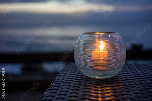 candle on a table with beach view at sunset