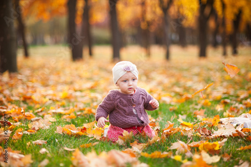 Little girl is playing in the autumn park with a smile.