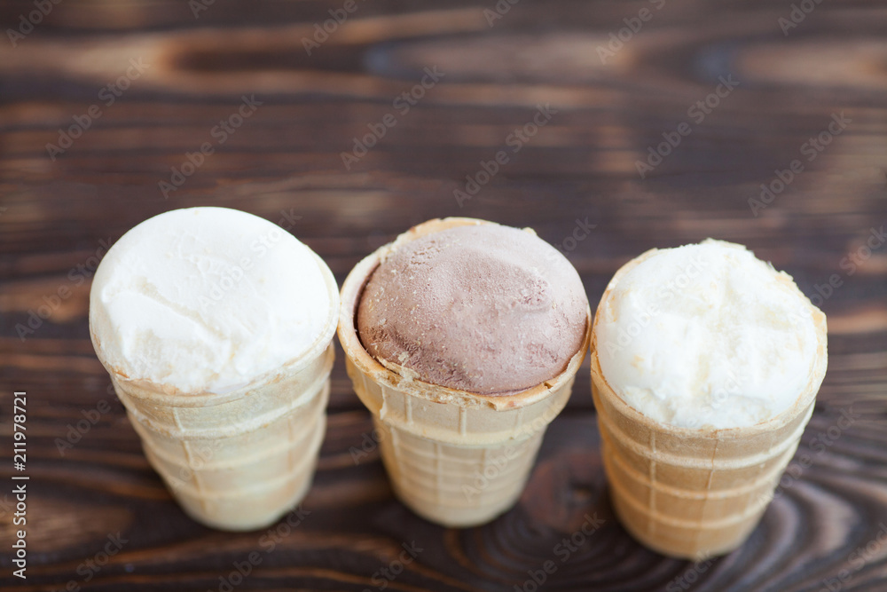 Homemade chocolate and vanilla ice cream in waffle cups on wooden background. Healthy summer food concept with copy space. Homemade chocolate and vanilla ice cream in waffle cups on wooden background. Healthy summer food concept with copy space.