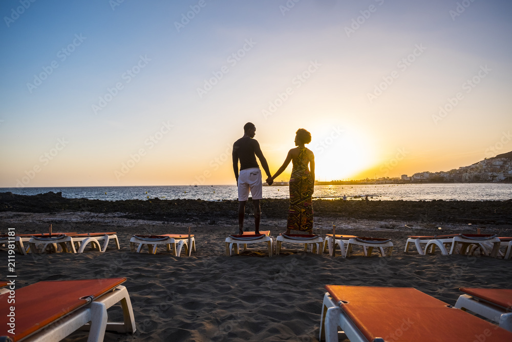 Φωτογραφία joyful and love concept for black race african couple standing at the beach and loving taking hands with a great beautiful sunset colored in front of them