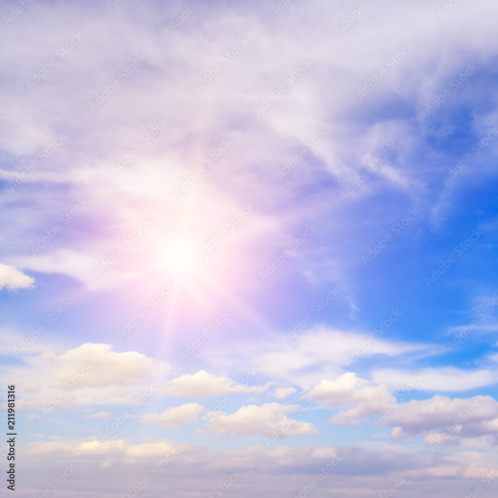 Sun on blue sky with white clouds.