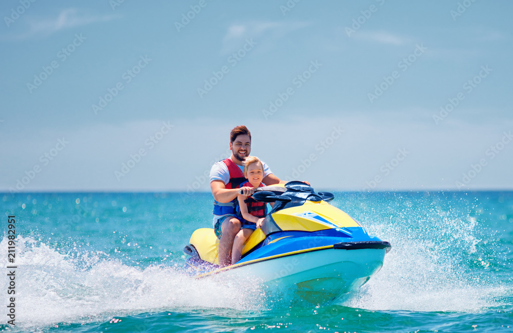 happy, excited family, father and son having fun on jet ski at summer vacation happy, excited family, father and son having fun on jet ski at summer vacation