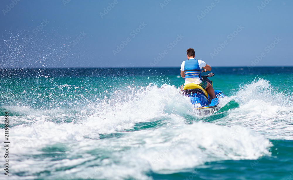 young adult man running the wave on jet ski during summer vacation young adult man running the wave on jet ski during summer vacation