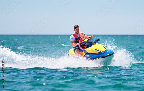 happy, excited family, father and son having fun on jet ski at summer vacation photo