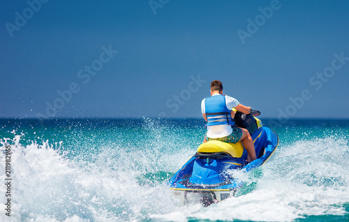 young adult man running the wave on jet ski during summer vacation