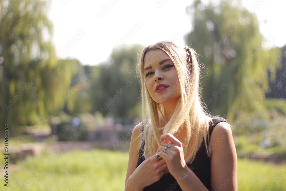 Young beautiful woman is warming in the sun sitting on the green grass in the park, on a wonderful summer day. Young beautiful woman is warming in the sun sitting on the green grass in the park, on a wonderful summer day.