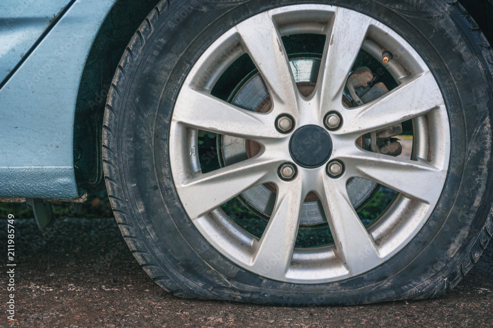 close up of a flat tire of a blue car on road