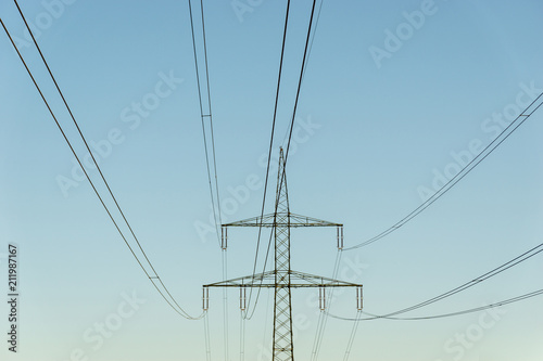 high voltage power line and pylon in front of blue sky