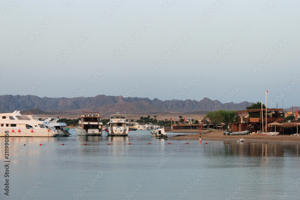 Bay and ships on the water. Boat station on the shore. Low mountains in the distance. Red sea coast, Egypt