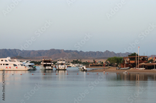 Bay and ships on the water. Boat station on the shore. Low mountains in the distance. Red sea coast, Egypt