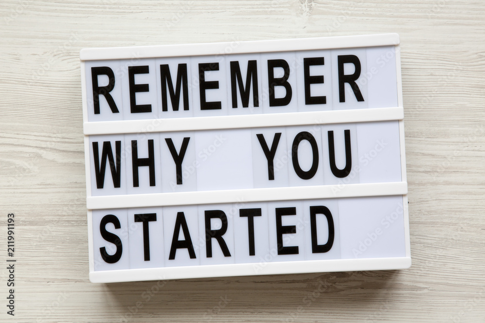 'Remember why you started' words on modern board over white wooden surface, from above. Top view, overhead, flat-lay.