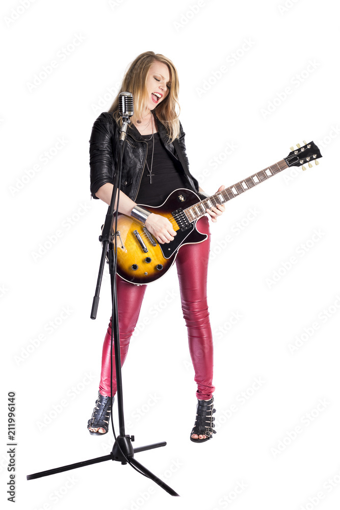 Sexy funny blonde girl guitarist plays solo by electric guitar, smiles,  sings into retro microphone. Woman teacher shows how to play song. Female  singer rock star in leather. rocker player singer foto